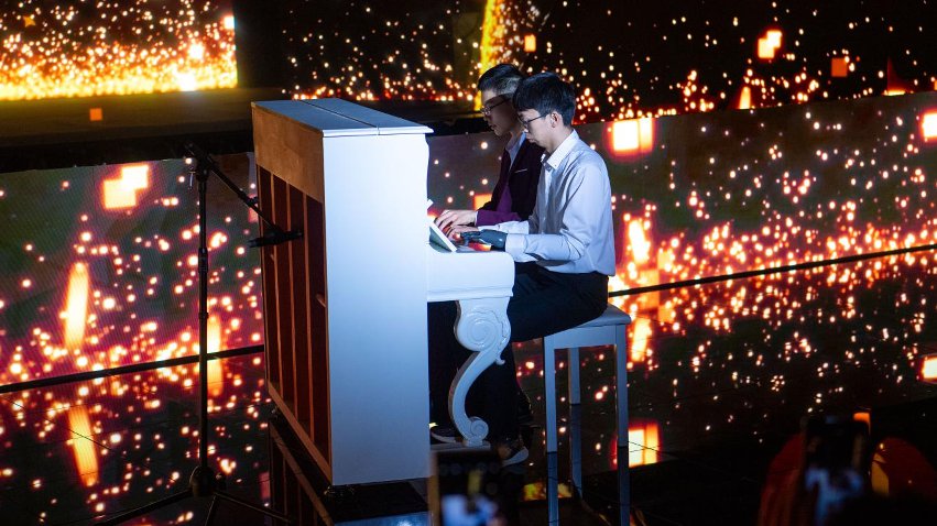 智能仿生手使用者古月與少年鋼琴家舒海峰合奏。主辦方供圖